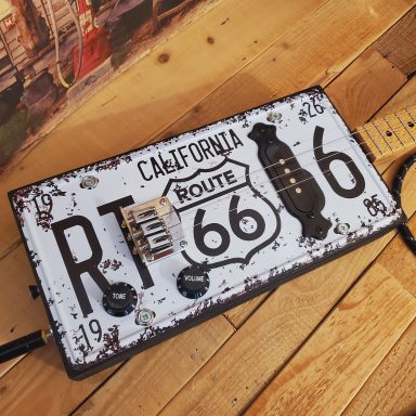 Guitare cigar box électrique blanche et noire réalisée avec une plaque d'immatriculation américaine Route 66. Guitare cigar box électrique blanche et noire réalisée avec une plaque d'immatriculation américaine Route 66.