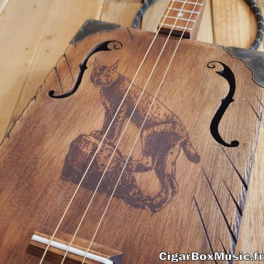 Guitare cigar box acoustique 3 cordes avec pré-ampli acoustique. Lynx gravé au laser et finition brun vintage. Guitare cigar box acoustique 3 cordes avec pré-ampli acoustique. Lynx gravé au laser et finition brun vintage.