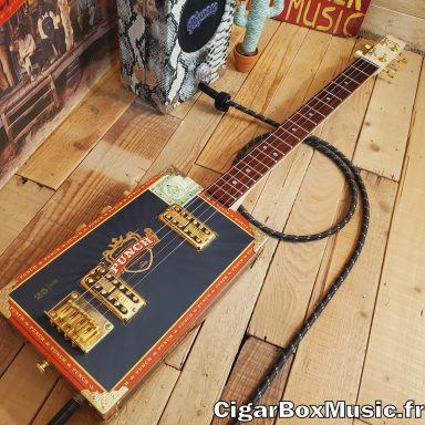 Guitare cigar box électrique 4 cordes avec accastillage or, boite importée US, touche rapportée et deux micros humbucker Gretsch FilterTron. Guitare cigar box électrique 4 cordes avec accastillage or, boite importée US, touche rapportée et deux micros humbucker Gretsch FilterTron.