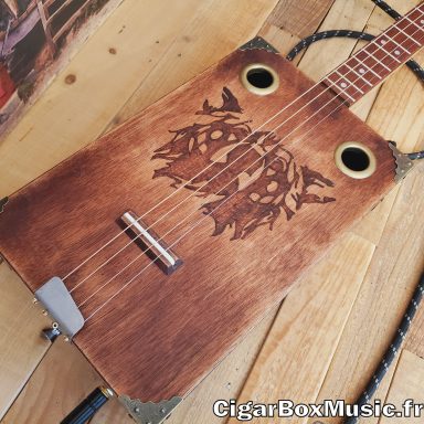 Guitare cigar box acoustique 4 cordes avec pré-ampli acoustique. Tête d'ours gravée au laser et finition brun vintage. Guitare cigar box acoustique 4 cordes avec pré-ampli acoustique. Tête d'ours gravée au laser et finition brun vintage.