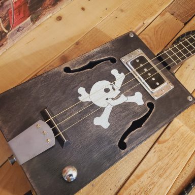 Guitare cigar box 3 cordes acoustique noire vintage avec crâne de pirate réalisé au pochoir.
