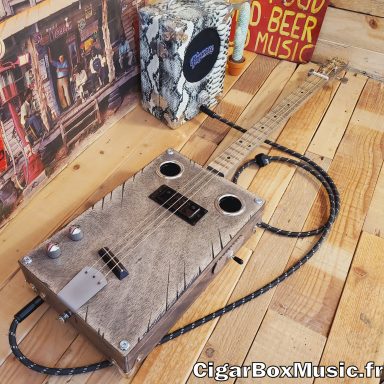 Guitare cigar box acoustique 3 cordes avec humbucker et piezo et switch 3 positions. Finition grise vintage. Guitare cigar box acoustique 3 cordes avec humbucker et piezo et switch 3 positions. Finition grise vintage.